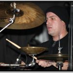 Derek Youngsma in Cap Behind Drumming Kit